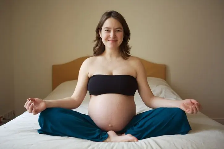 Pregnant Woman Meditating In Bed